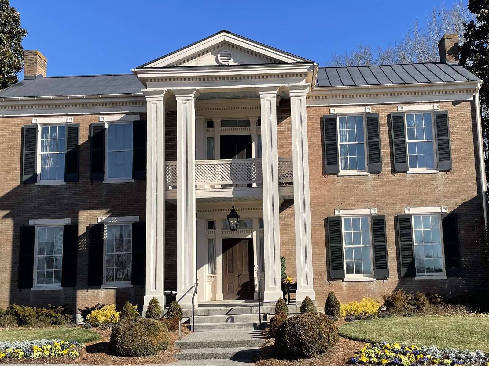 Pleasant Hill, a two-story red-brick Greek Revival house with a two-story white portico on Doric columns, seen across a lawn