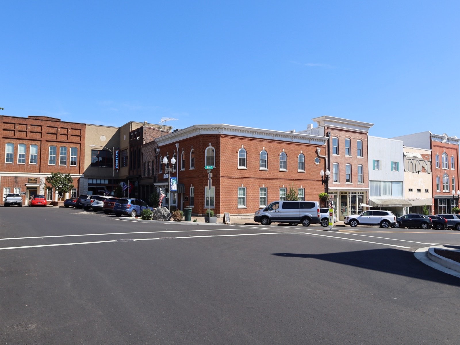 A row of nineteenth-century brick storefronts along a wide resurfaced street on Columbia's public square