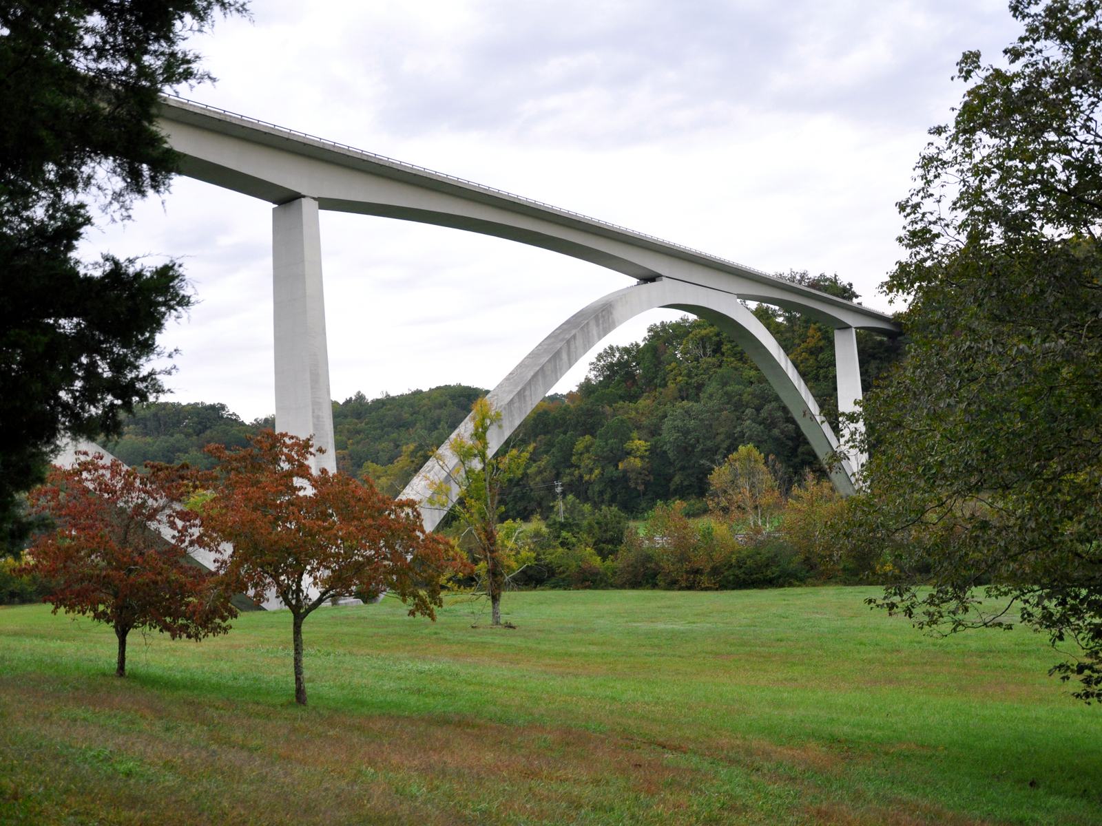 The Natchez Trace Parkway's white concrete double-arch bridge spanning a wooded hollow above a mown field