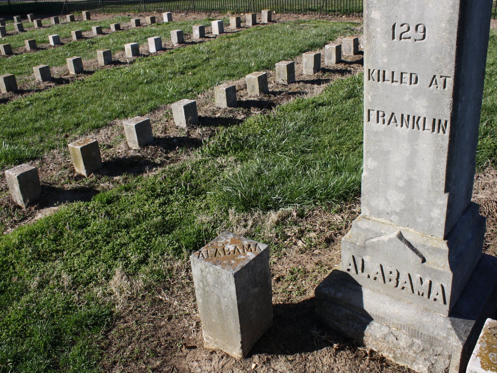 Rows of small square headstones on a lawn beside a stone obelisk marked Alabama at the McGavock Confederate Cemetery