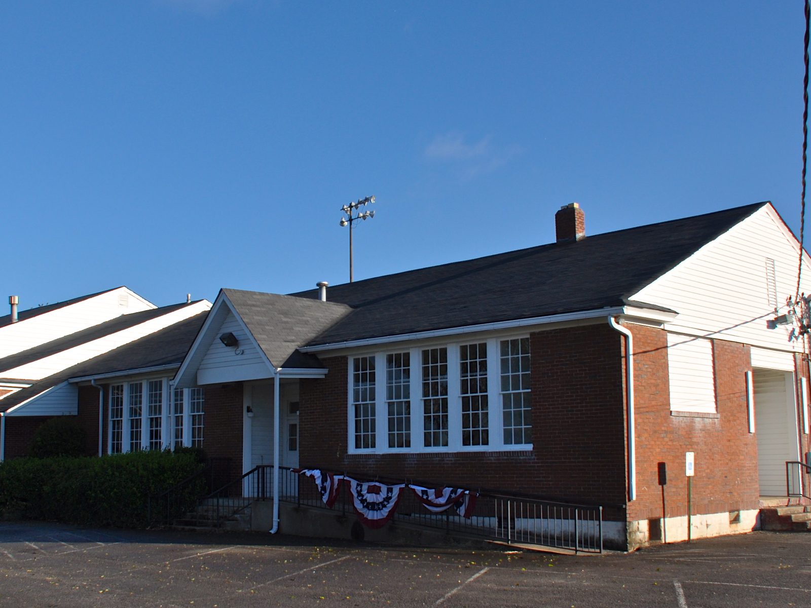 The Historic Nolensville School, a low red-brick 1937 schoolhouse with tall white-framed windows and a gabled entry porch