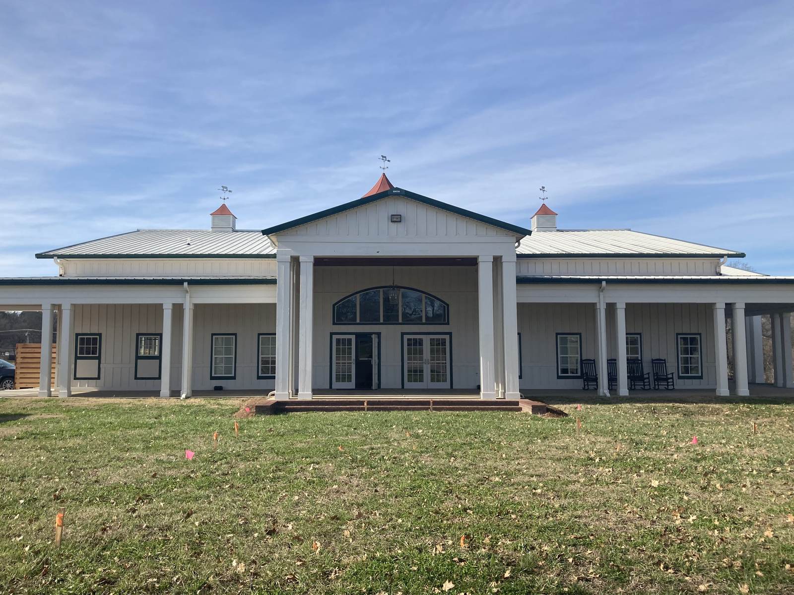 A one-story board-and-batten railroad depot painted grey with a deep bracketed roof overhang and a covered porch